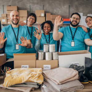 Multi-ethnic group of people, diverse volunteers packing donation boxes in charity food bank.