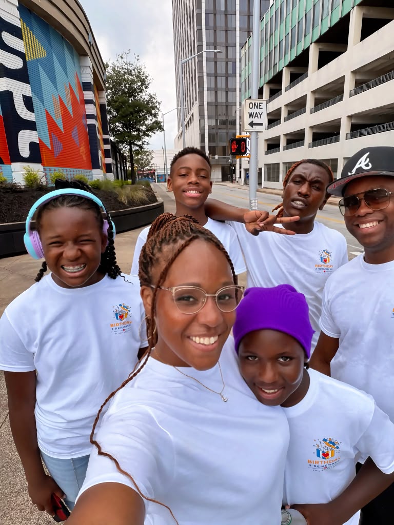 The Birthday 2 Remember family together in downtown Atlanta, wearing organization shirts and smiling for a selfie.